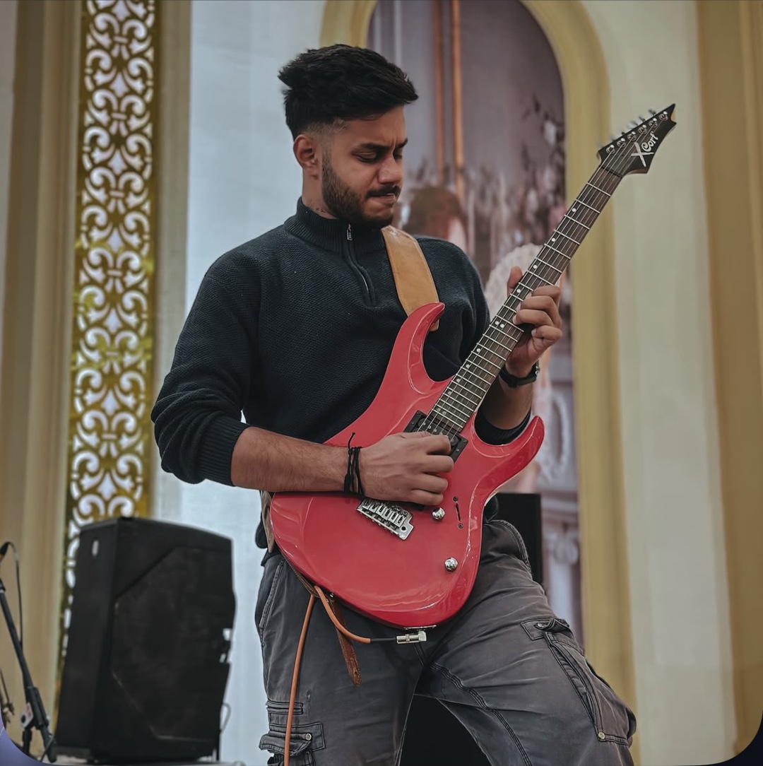 Arya Sen playing red electric guitar live